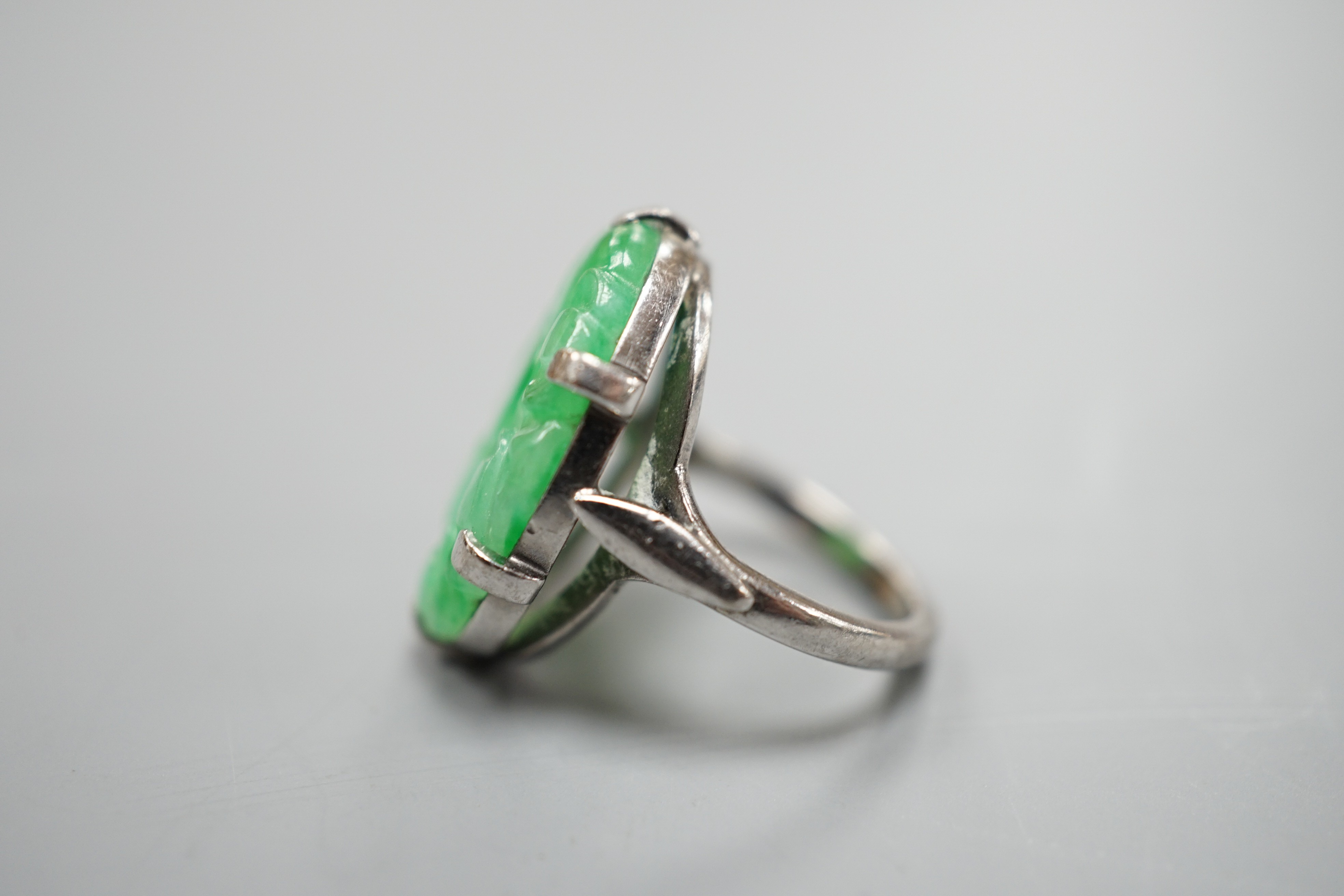 A white metal and oval jade set ring, carved with fruit, size F, gross weight 6.3 grams.